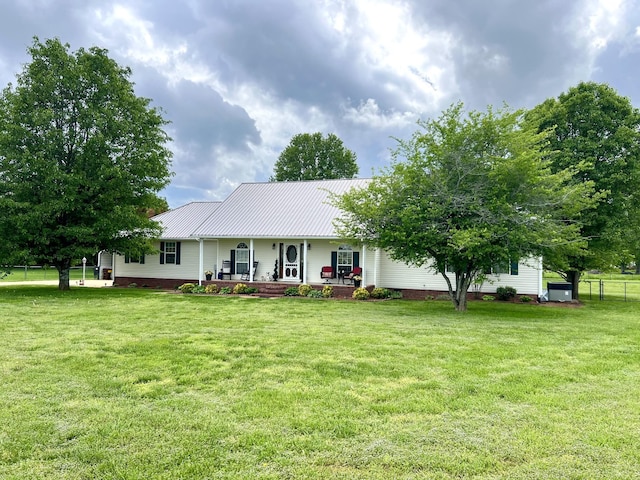 single story home featuring metal roof, a front lawn, covered porch, and fence