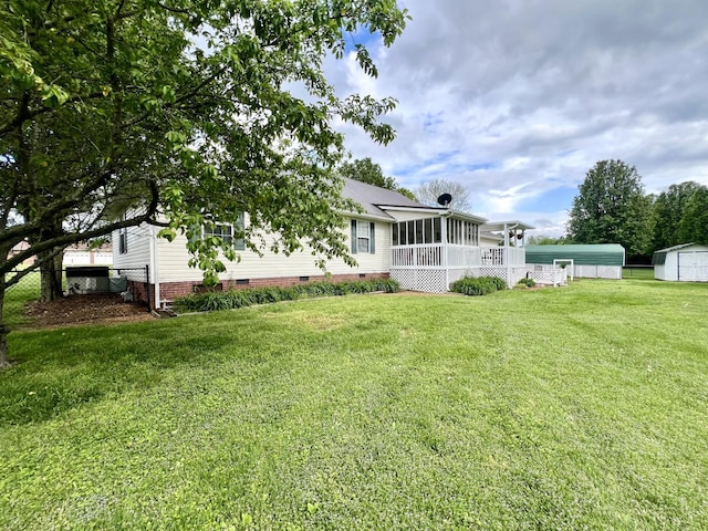 back of house featuring a storage unit, an outbuilding, crawl space, a yard, and a sunroom