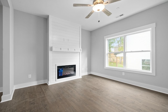 unfurnished living room with a fireplace, dark wood-style flooring, visible vents, and baseboards