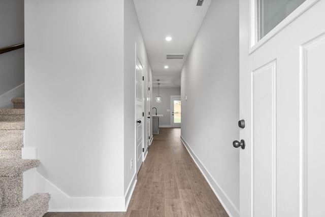 hallway with recessed lighting, wood finished floors, stairway, baseboards, and visible vents