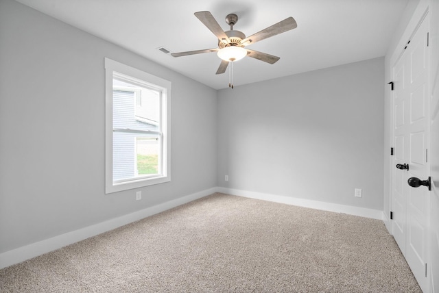 carpeted spare room with a ceiling fan, visible vents, and baseboards