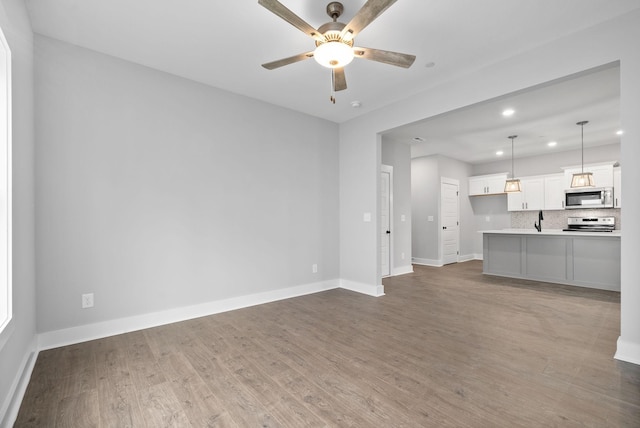 unfurnished living room featuring baseboards, light wood-type flooring, ceiling fan, and recessed lighting