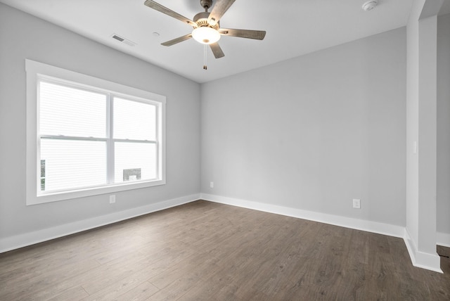 empty room with baseboards, visible vents, ceiling fan, and dark wood-type flooring
