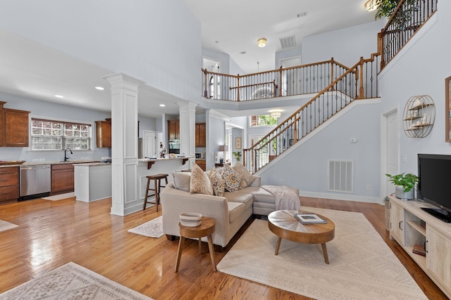 1004 Sattui Ct, Franklin, TN 37064 - living area featuring a towering ceiling, light wood-style flooring, stairway, ornate columns, and baseboards