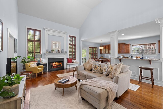 1004 Sattui Ct, Franklin, TN 37064 - living room with a lit fireplace, wood finished floors, ornate columns, and high vaulted ceiling