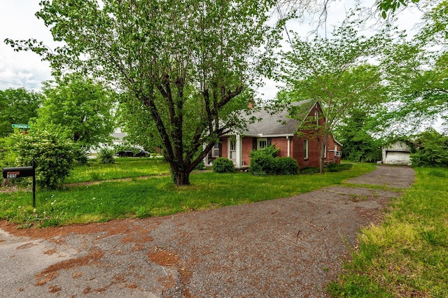 view of front of property featuring an outdoor structure, brick siding, roof with shingles, a detached garage, and a front yard