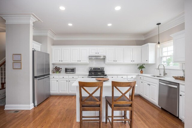 kitchen with a sink, appliances with stainless steel finishes, under cabinet range hood, and white cabinets
