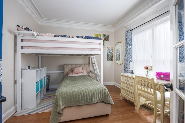 bedroom with crown molding, baseboards, and wood finished floors