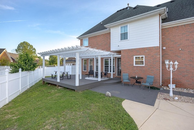 rear view of house featuring a deck, brick siding, fence, a yard, and a pergola