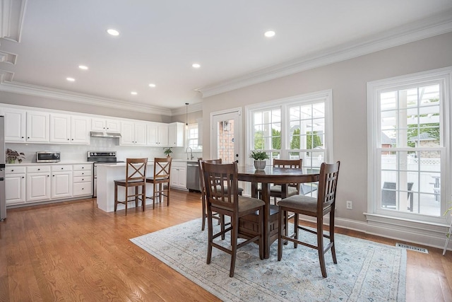 dining space with visible vents, plenty of natural light, ornamental molding, and wood finished floors