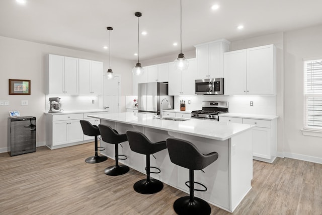 kitchen with stainless steel appliances, baseboards, a sink, and a kitchen breakfast bar