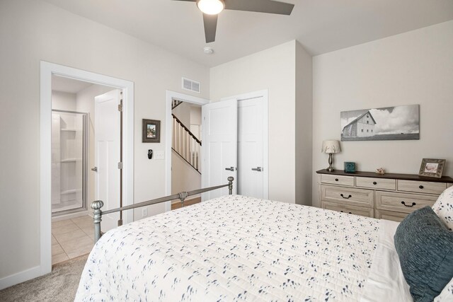 bedroom featuring visible vents, baseboards, ensuite bathroom, light colored carpet, and a ceiling fan