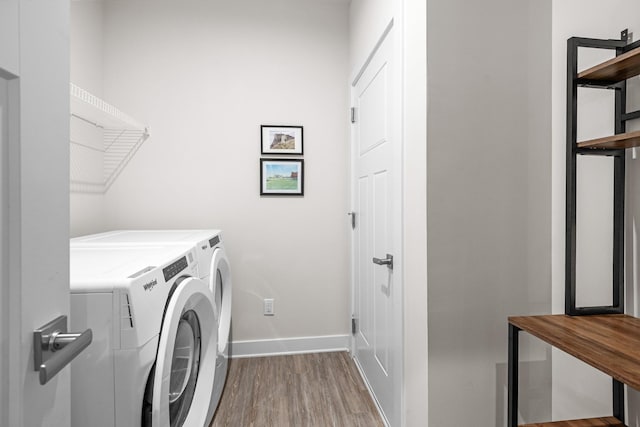 laundry room featuring baseboards, laundry area, wood finished floors, and washer and dryer