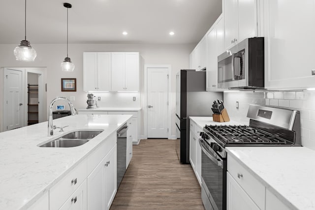 kitchen with white cabinetry, appliances with stainless steel finishes, a sink, and tasteful backsplash