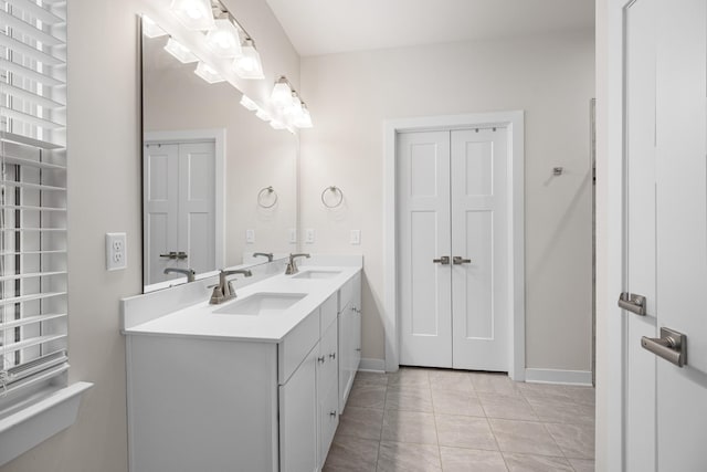 full bath with double vanity, baseboards, and a sink