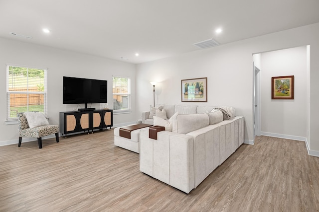 living room with visible vents, light wood finished floors, and baseboards