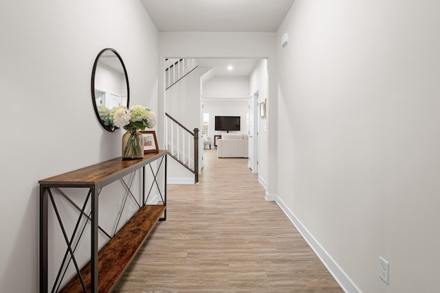 hallway featuring recessed lighting, baseboards, stairs, and wood finished floors