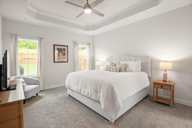 bedroom featuring carpet floors, a tray ceiling, visible vents, and multiple windows