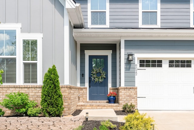 doorway to property with a garage, board and batten siding, and concrete driveway