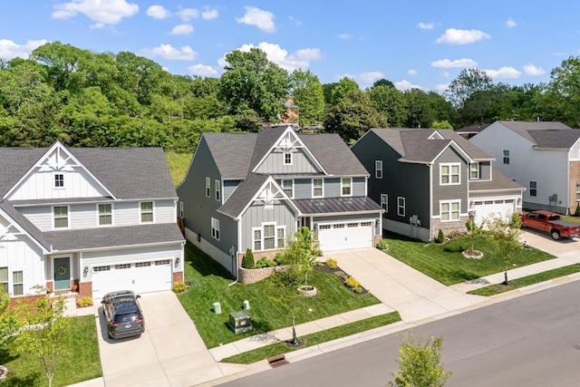 view of front of property featuring a garage, board and batten siding, concrete driveway, and a front lawn
