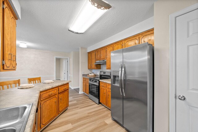 3844 Marla Cir, Clarksville, TN 37042 - kitchen featuring light wood finished floors, a sink, brown cabinets, stainless steel appliances, and under cabinet range hood
