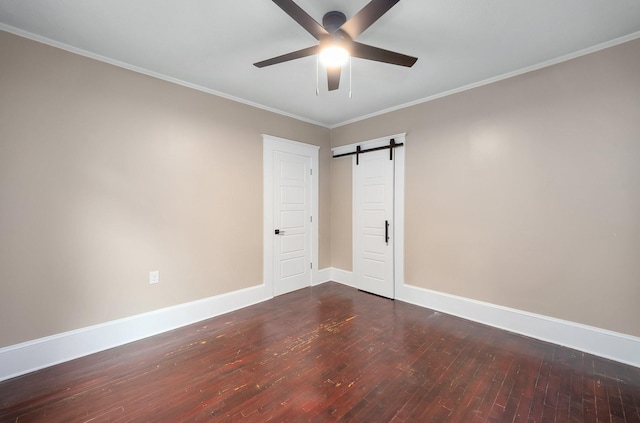unfurnished room with crown molding, a barn door, baseboards, wood-type flooring, and a ceiling fan