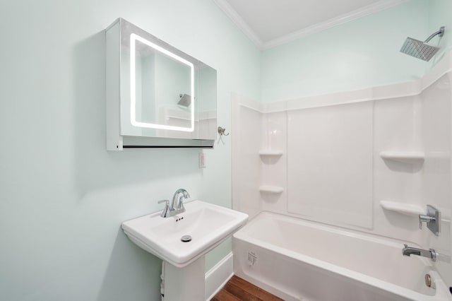 full bathroom with wood finished floors,  shower combination, ornamental molding, and a sink