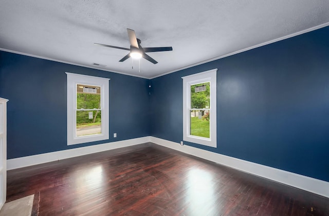 empty room with wood finished floors, ornamental molding, ceiling fan, baseboards, and visible vents