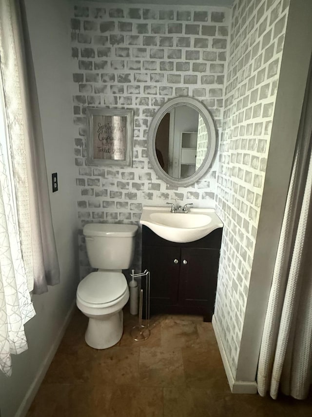 bathroom with baseboards, toilet, and vanity