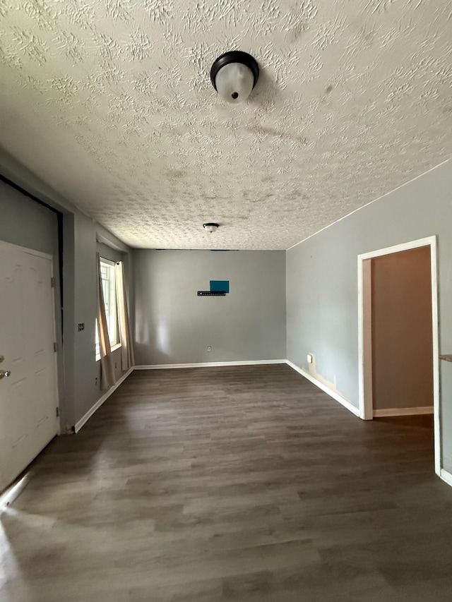 spare room with dark wood-style flooring, baseboards, and a textured ceiling