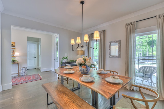 dining area with baseboards, crown molding, and light wood-style flooring