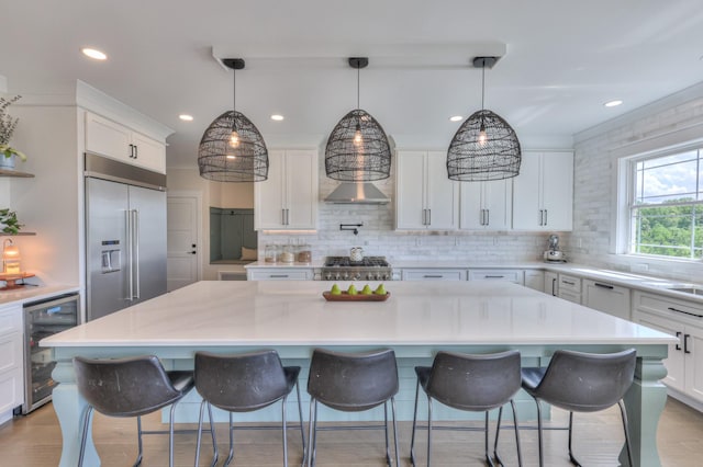 kitchen with built in refrigerator, wine cooler, tasteful backsplash, and a center island