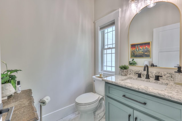 bathroom with baseboards, toilet, vanity, and plenty of natural light
