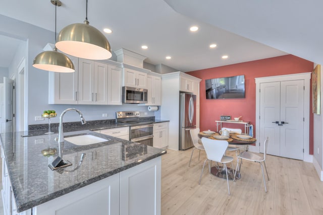 kitchen featuring white cabinets, a sink, appliances with stainless steel finishes, recessed lighting, and a peninsula