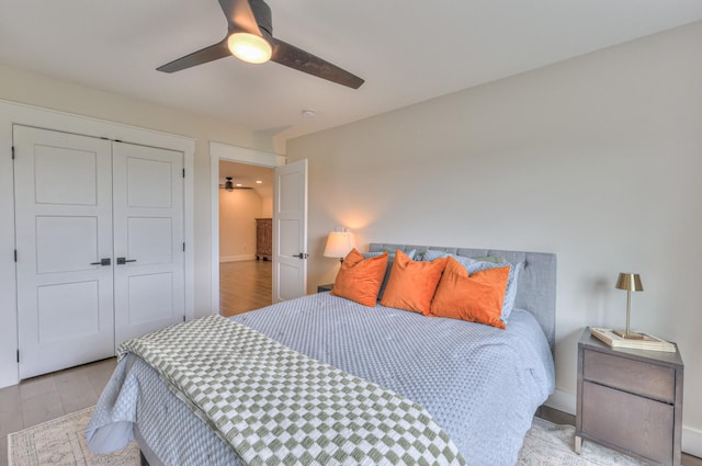 bedroom with baseboards, wood finished floors, a ceiling fan, and a closet