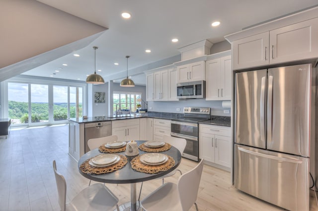 kitchen featuring a sink, stainless steel appliances, light wood-type flooring, recessed lighting, and a peninsula