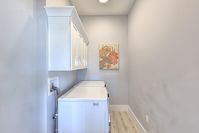 clothes washing area featuring washer and dryer, cabinet space, baseboards, and light wood-type flooring