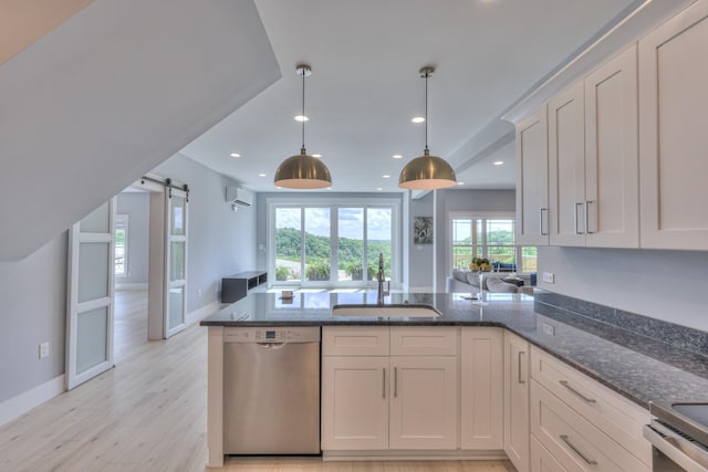 kitchen featuring dark stone countertops, a wall unit AC, a sink, stainless steel appliances, and a peninsula