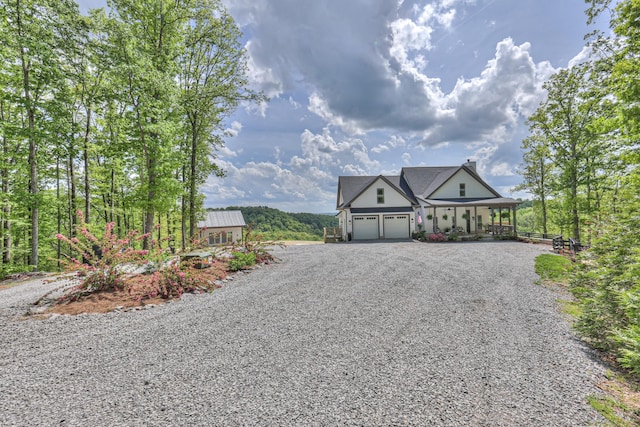 view of front facade with a porch, gravel driveway, and a garage