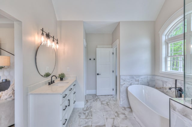 bathroom with a freestanding tub, vanity, and marble finish floor