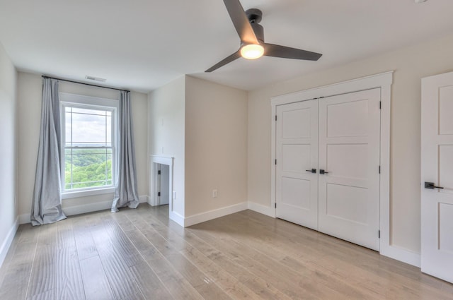 unfurnished living room with baseboards, light wood-type flooring, and a ceiling fan