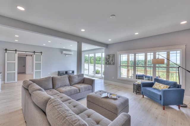 living room with recessed lighting, a barn door, light wood finished floors, an AC wall unit, and baseboards