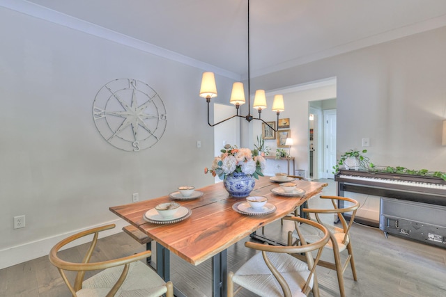 dining space with an inviting chandelier, wood finished floors, crown molding, and baseboards