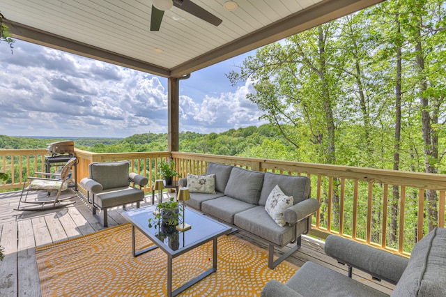 deck featuring an outdoor hangout area, a ceiling fan, and a view of trees