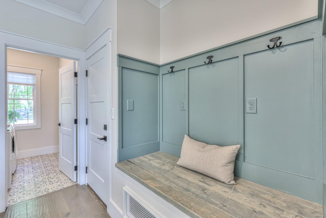 mudroom with wainscoting, wood finished floors, crown molding, and a decorative wall