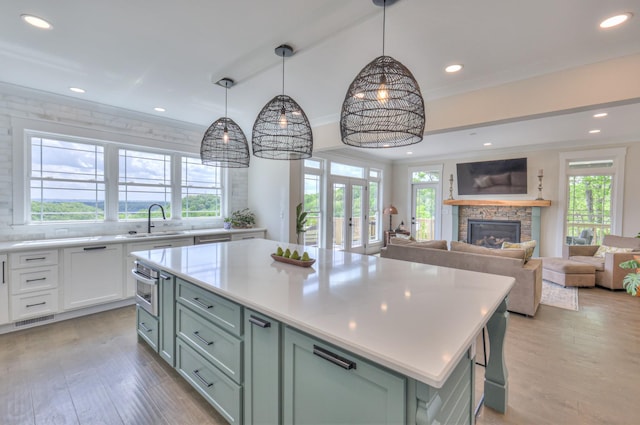 kitchen featuring light wood-style floors, light countertops, a fireplace, a sink, and a center island