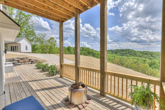 wooden deck with an outdoor fire pit and a forest view