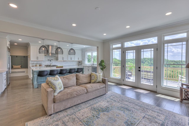 living area with crown molding, recessed lighting, french doors, and wood finished floors