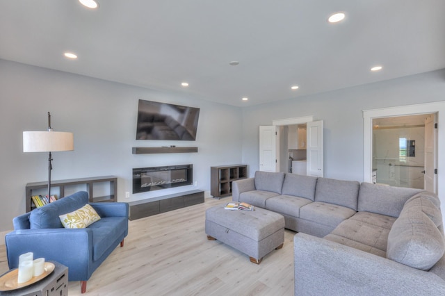 living room with recessed lighting, wood finished floors, and a glass covered fireplace
