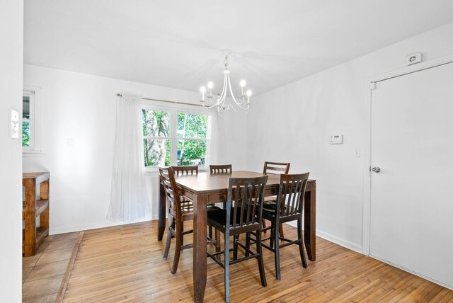 dining area featuring an inviting chandelier, baseboards, and light wood-type flooring